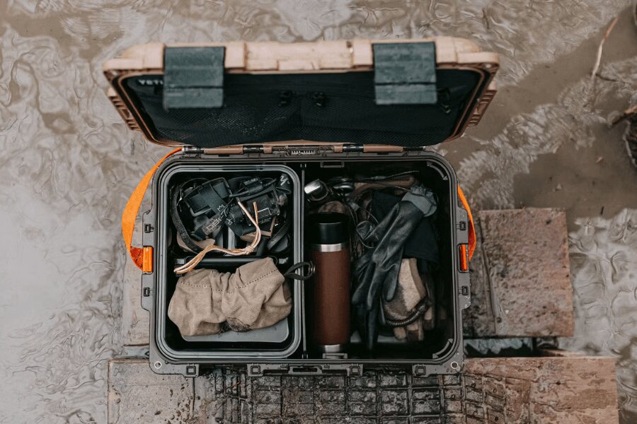 Odolný gear box YETI LoadOut GoBox s vybavením položený v mokrom teréne