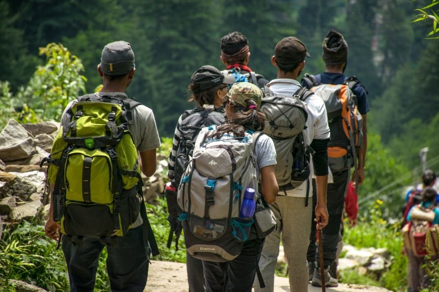 Skupina turistov pochodujúcich s batohmi v blízkosti stromov